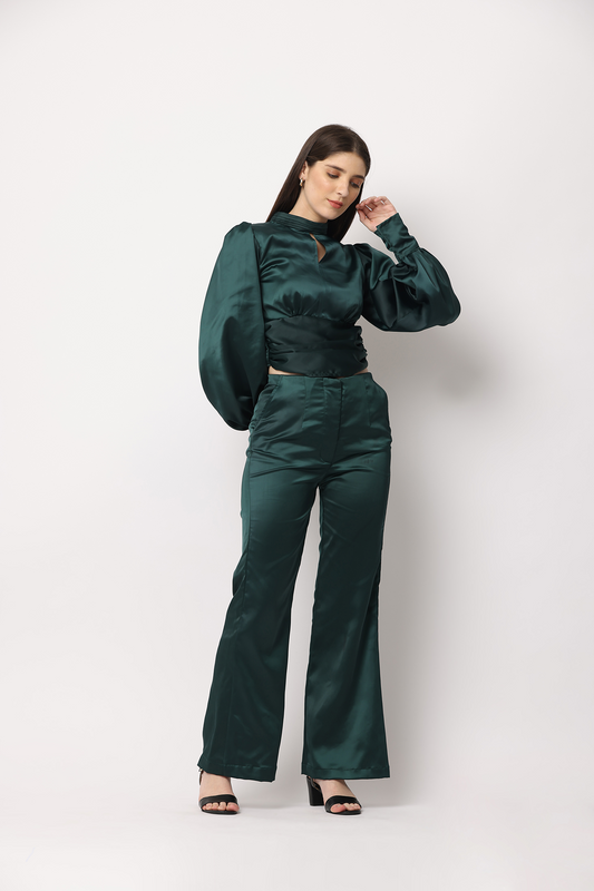 This elegant ensemble features a cropped silhouette with full sleeves and a captivating open-back design adorned with a delicate tie detail. The high-waist trousers are accentuated by seam detailing on the front and back, while the subtle satin shine of green lends a luxurious feel. 