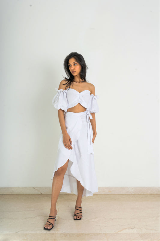 Crafted with fine linen fabric and featuring a one-of-a-kind asymmetrical cut design, this set has a strapless pleat detailed crop top with puff sleeves and a wrap-around skirt in white fabric.