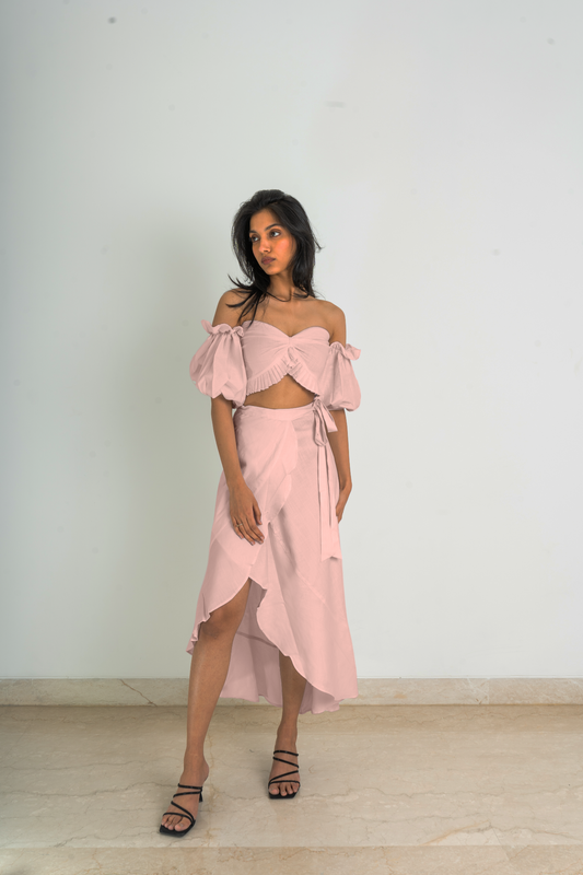 Crafted with fine linen fabric and featuring a one-of-a-kind asymmetrical cut design, this set has a strapless pleat detailed crop top with puff sleeves and a wrap-around skirt in pink shade.