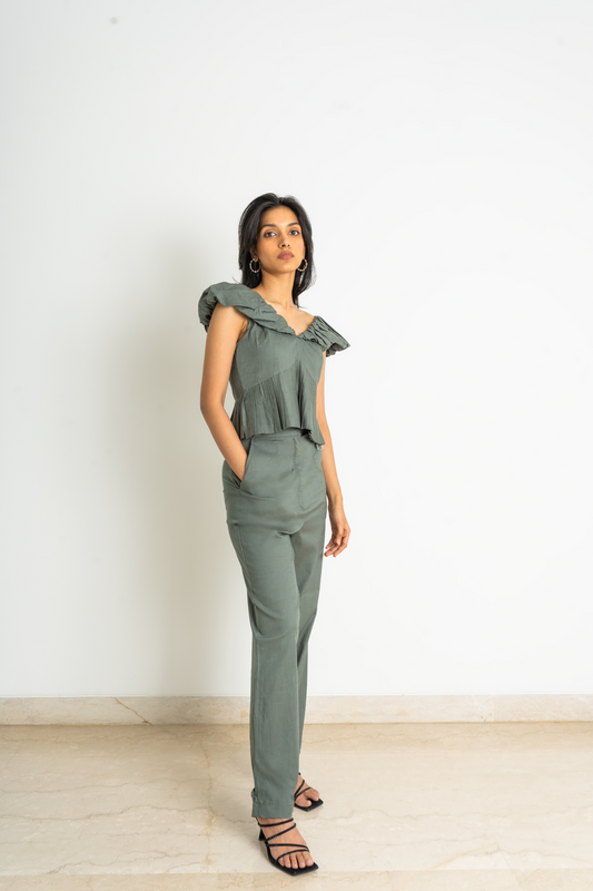 This detail-oriented, ruffled neck deep green linen blend co-ord is a pleated peplum top and straight pants set. The pants can be adjusted to both a straight fit and a slim fit for a versatile look.