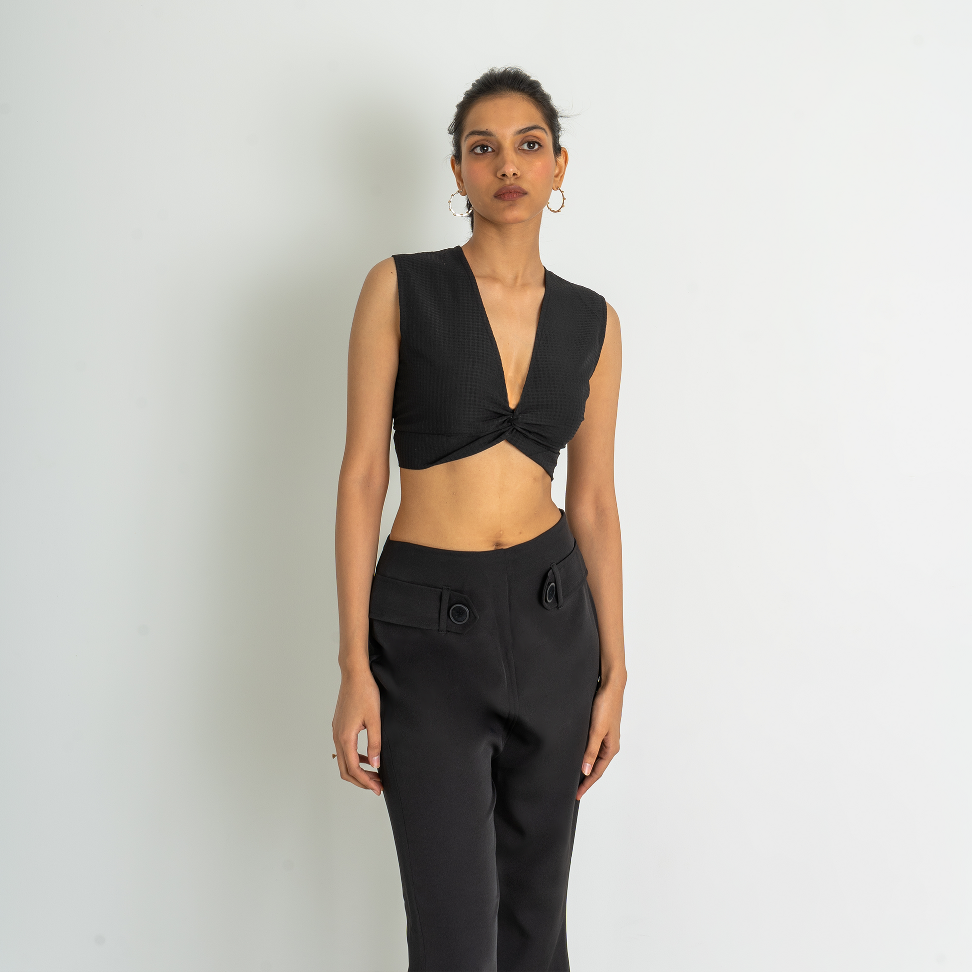 Cropped blouse in woven fabric made from cotton with a deep, V-shaped neckline and a decorative knot detail at the front. Sleeveless and a partially open back with a hook-and-eye fastener at the top and wide ties at the hem.